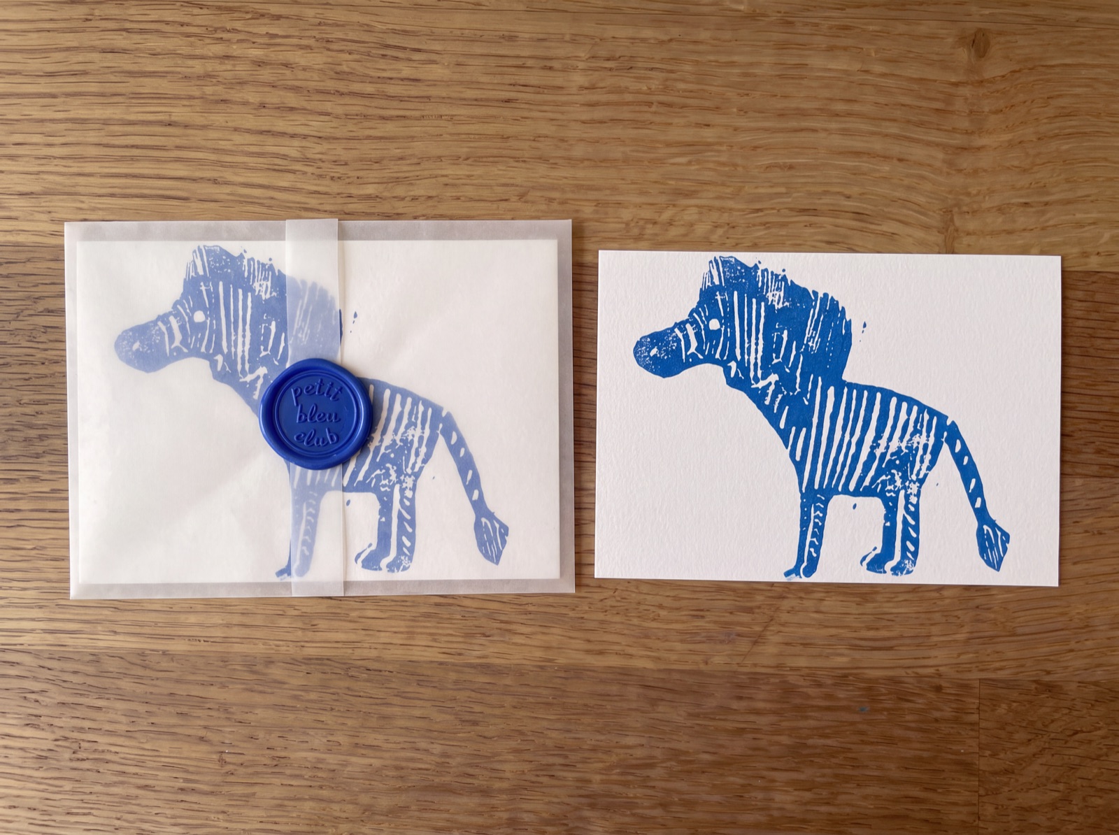 Petit Bleu Club August 2026: hand-pulled blue zebra print and a glassine envelope sealed with a Petit Bleu Club wax seal